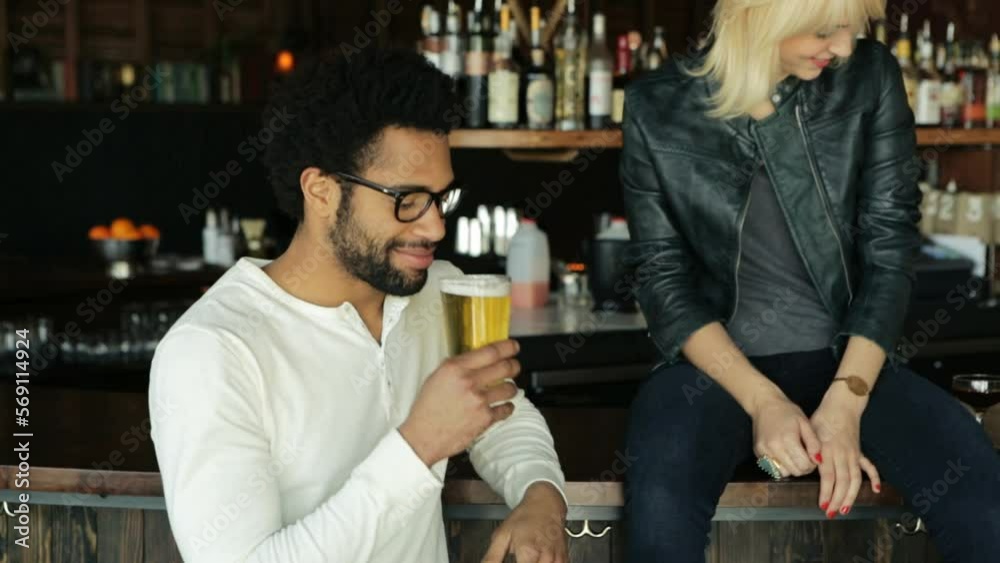 African american man with glasses receives a beer while a caucasian bl