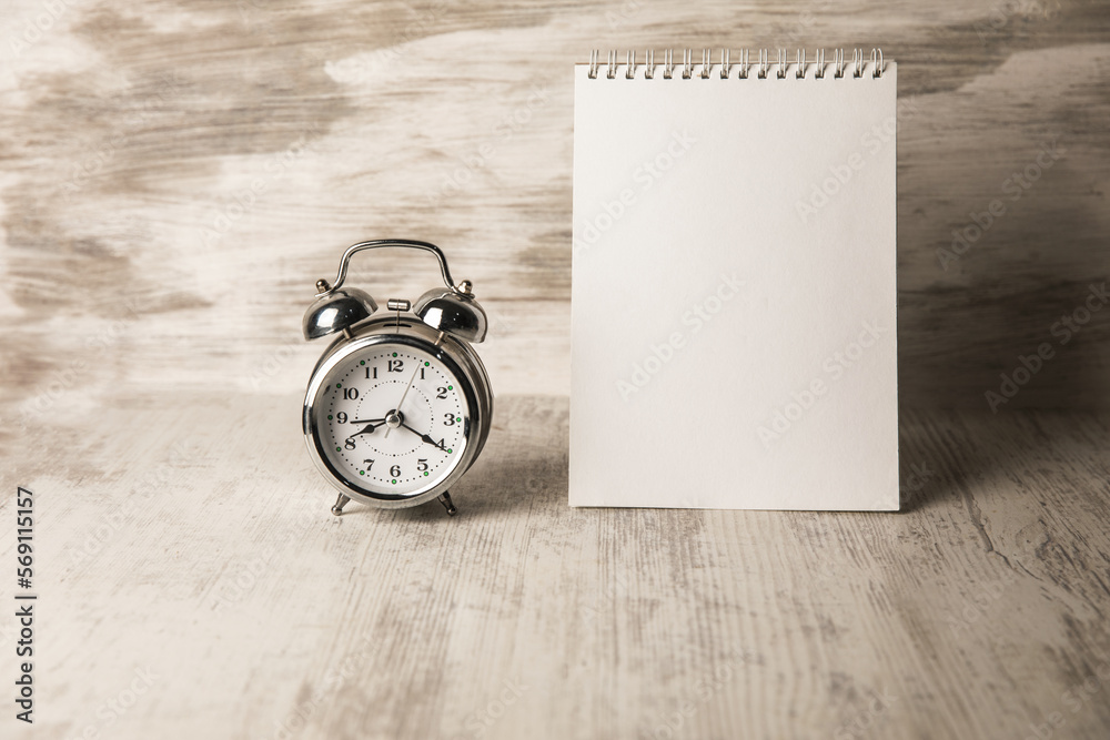 Alarm clock and notebook on the table