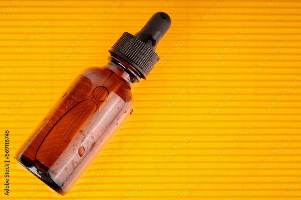 On background of yellow, there is serum container. On background of yellow, there is serum container.