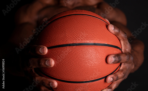african man hands holding a basketball, black background © Cavan