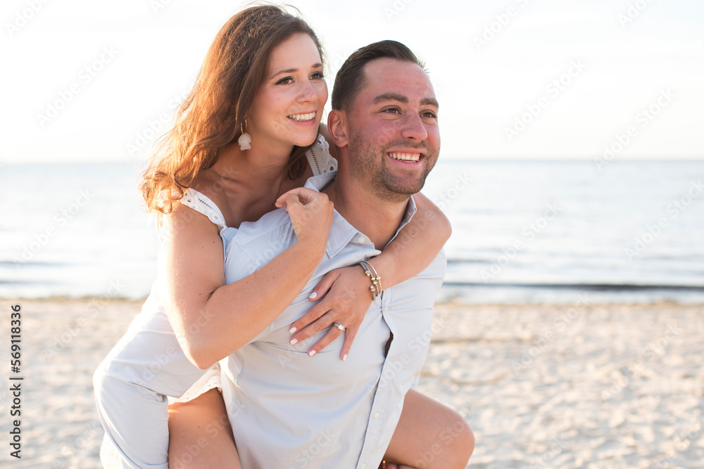 man carrying woman on back at beach laughing