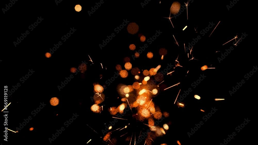Burning red hot sparks rise from large fire in the night sky