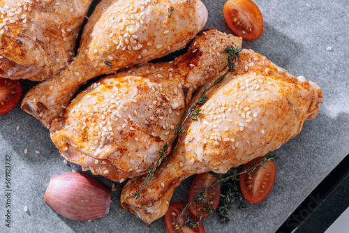 chicken drumsticks with spices, paprika and sesame seeds, ready to bake on a baking sheet