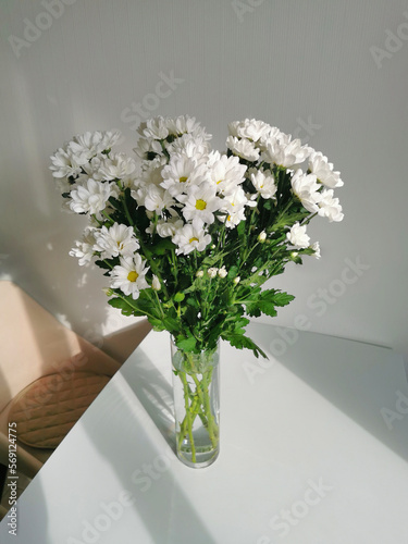 Bouquet of white chrysanthemums in a glass vase on the table.