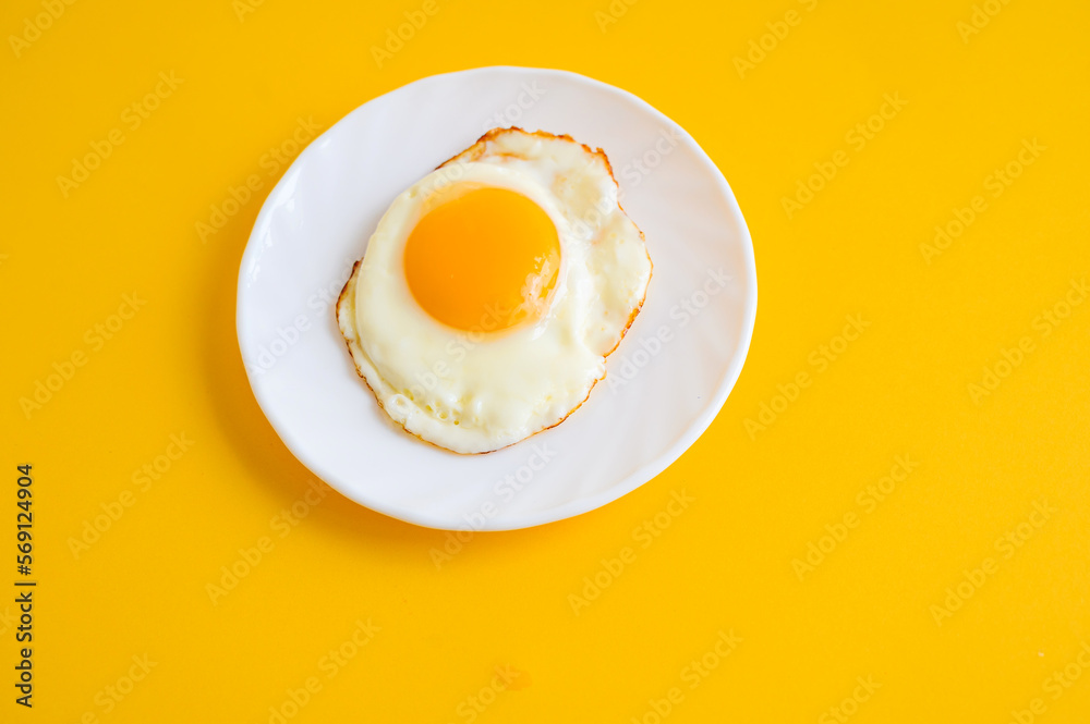 Fried egg on a white plate. Fried eggs on a yellow background. Breakfast Fried egg on a white plate. Fried eggs on a yellow background. Breakfast