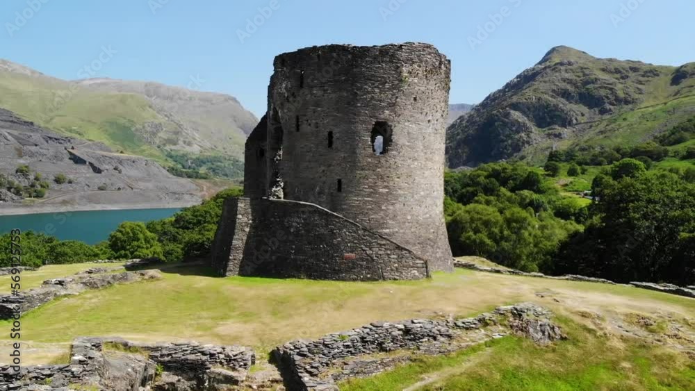 Aerial shot of castle ruins in Wales with the beautiful countryside in the background including a lake, rolling hills, and trees. Shot during a warm and sunny day Aerial shot of castle ruins in Wales with the beautiful countryside in the background including a lake, rolling hills, and trees. Shot during a warm and sunny day