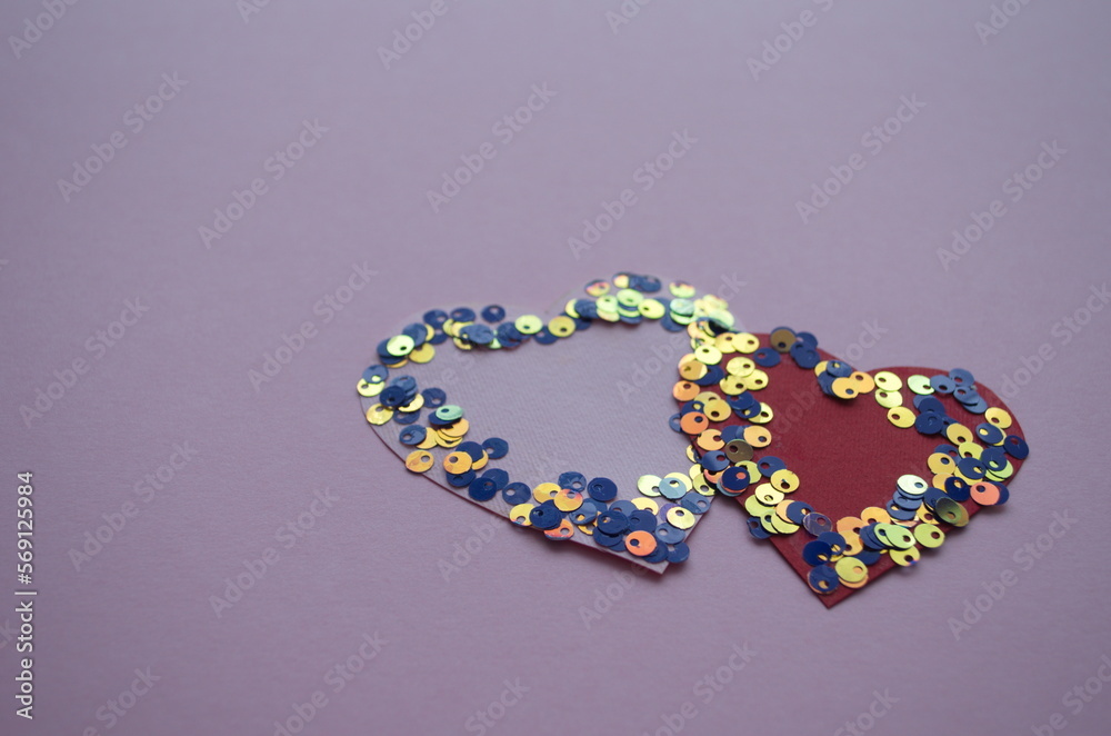 Heart shaped frame made of shiny sequins on a blue background. Festive texture for Valentines Day, Mothers Day, Womens Day
