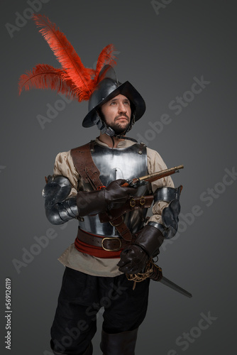 Portrait of medieval conquistador dressed in plate armour holding epee.