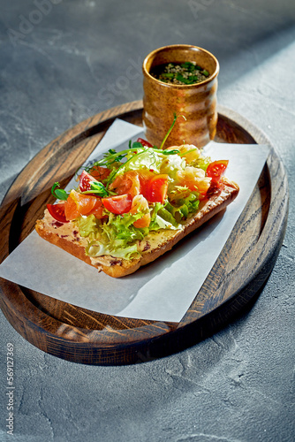 Toast with salmon, cherry tomatoes and lettuce on a wooden board. Concrete background, morning light. Food for breakfast. Close up