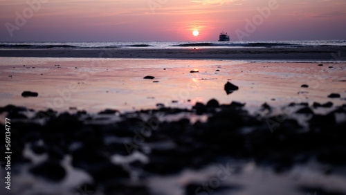 Beautiful view sunset over sea, ocean waves crashing on a stones beach