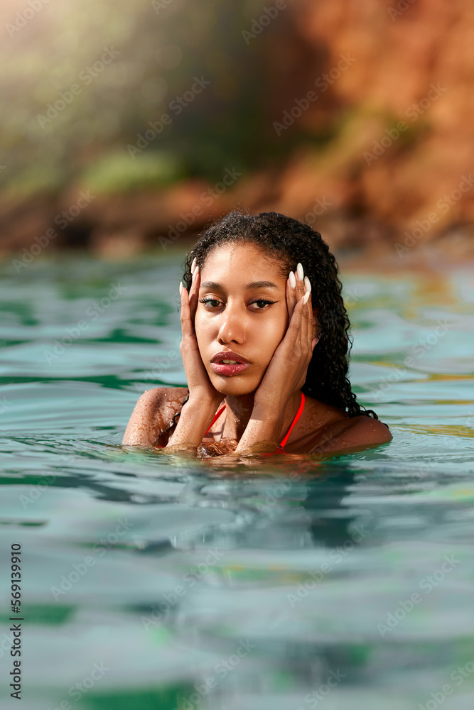 Portrait of serene looking attractive young black female posing in bikini in water. African model posing in the sea. Multiracial woman posing at the beach in ocean. Fashion portrait of black woman