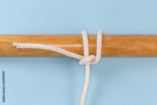 Tightened rope knot Ossel hitch tied around a wooden pole