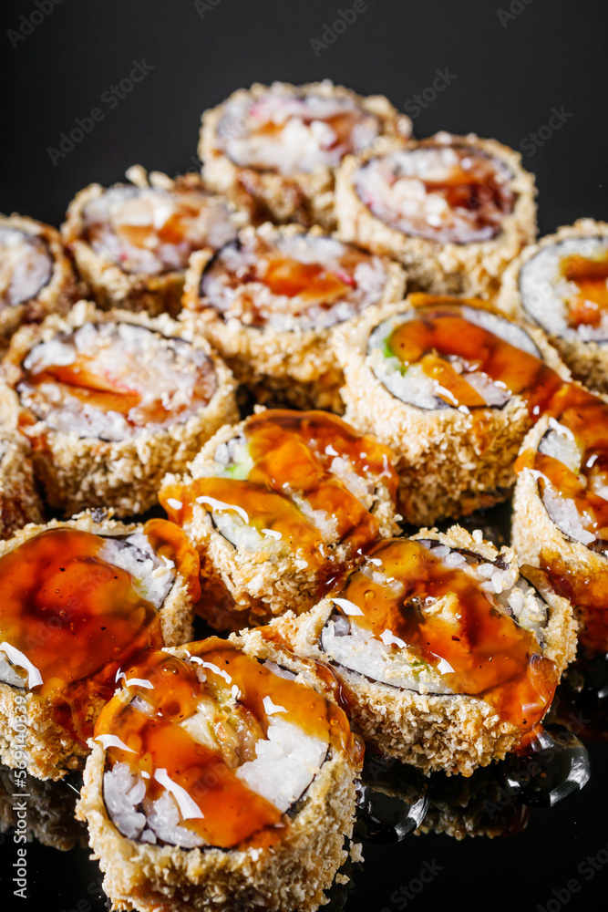 hot sushi roll tempura with eel shrimp crab salmon cream cheese cucumber avocado unagi on a black mirror background hot sushi roll tempura with eel shrimp crab salmon cream cheese cucumber avocado unagi on a black mirror background