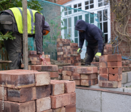 Two construction workers laying bricks as part of a renovation of an Edwardian suburban house in north London, UK photo
