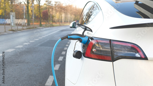 Electric vehicle charging at a public charging station in a city setting. New energy vehicles, eco-friendly alternative energy for cars. Electric cars are becoming more common and gaining popularity.
