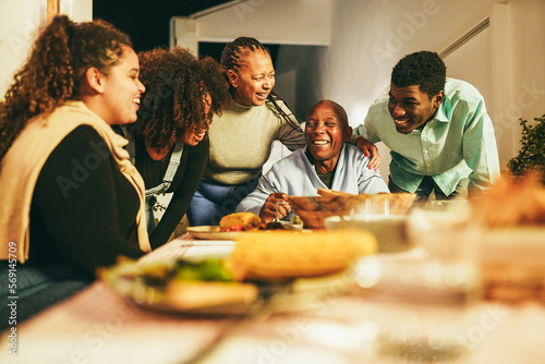 Happy african family eating dinner together at home terrace outdoor - Soft focus on senior woman face