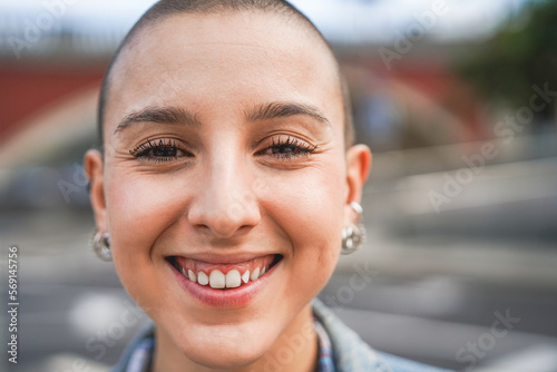 Bald girl smiling on camera outdoor - Focus on face