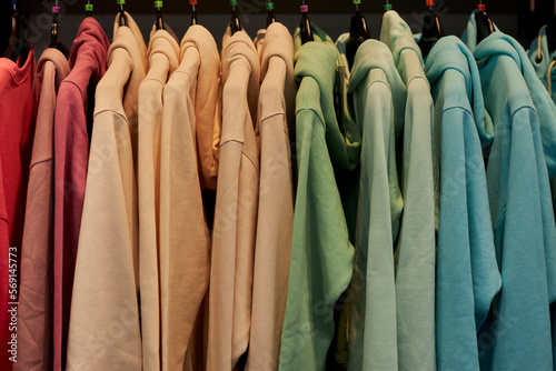 multi-colored sweatshirts on hangers in the store. Bright colorful sweatshirts hang in a fashion store. multi-colored sweatshirts on a hanger in a clothing store.