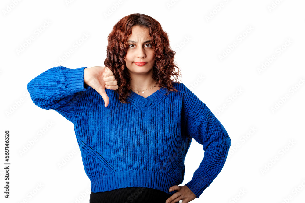 Millennial woman wearing sweater standing isolated over white background looking unhappy and angry showing rejection and negative with thumbs down gesture. Bad expression. Don't do it! Millennial woman wearing sweater standing isolated over white background looking unhappy and angry showing rejection and negative with thumbs down gesture. Bad expression. Don't do it!