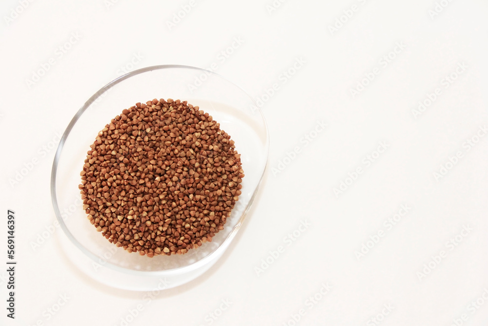 Small brown grains of natural buckwheat in a decorative transparent glass plate Small brown grains of natural buckwheat in a decorative transparent glass plate