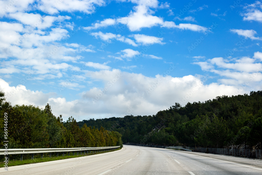 Highway and nature in spring with blue skies and clouds, no traffic Highway and nature in spring with blue skies and clouds, no traffic