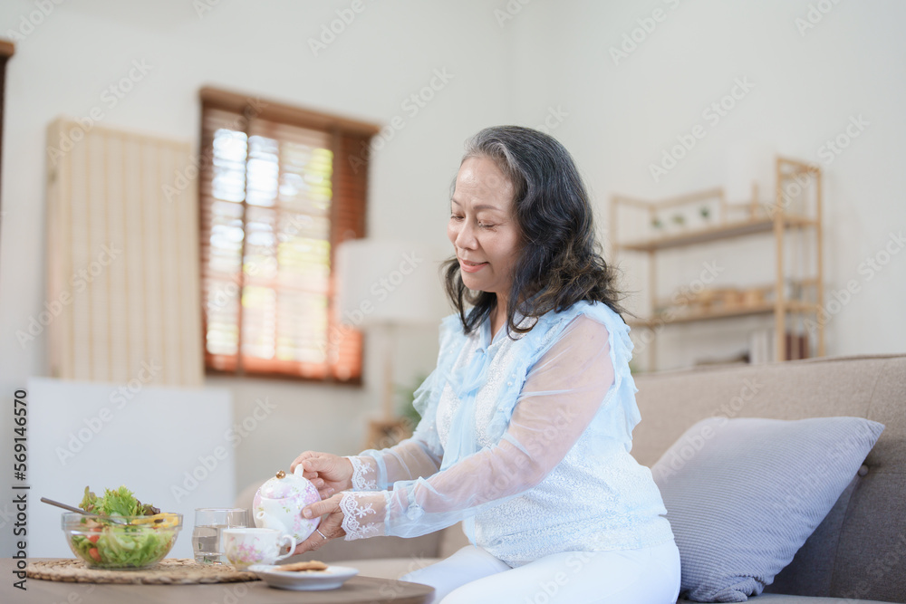 Portrait of an elderly Asian woman drinking healthy tea while eating vegetable salad and snack.