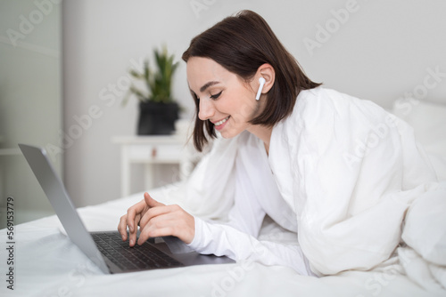 Positive relaxed young lady chilling in bed at home