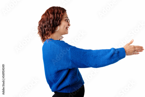 Woman wearing sweater standing isolated over white background giving hand for handshake, greeting with smile. The concept of meeting. Holds out hand to the empty copy space and wants to shake hands.