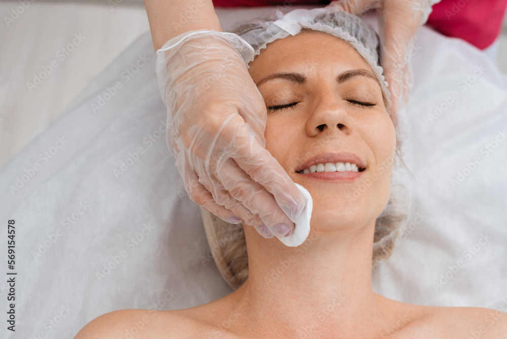 Сosmetologist prepares client skin for procedure in beauty salon