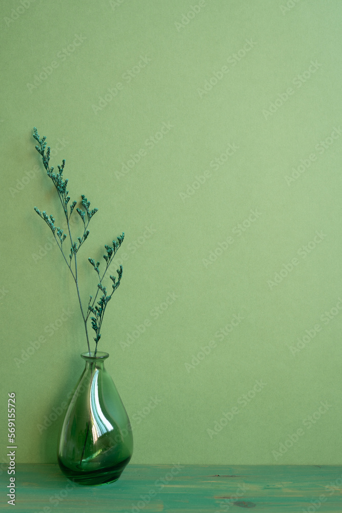 Glass vase of dry flower on wooden table. green wall background. home interior, minimal, copy space