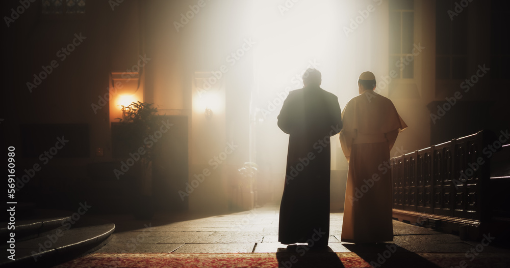 In The Church, A Priest And Pope Share A Conversation Of Faith, Reverence, Hope, Discussing Gospels and Teaching of Jesus Christ and Holy Book. Blessing Light From Tainted Window Shines on Them. - obrazy, fototapety, plakaty 