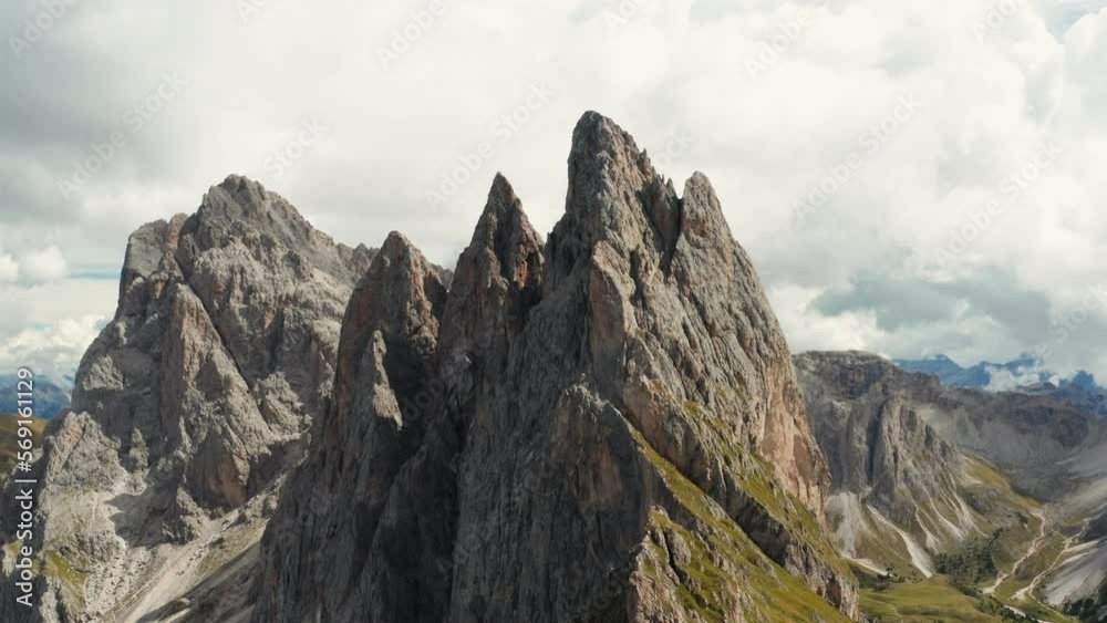 Rocky bare peaks of Seceda mountain against cloudy sky. Giant ridgeline in touristic Italian Alps aerial view from observation point on slope