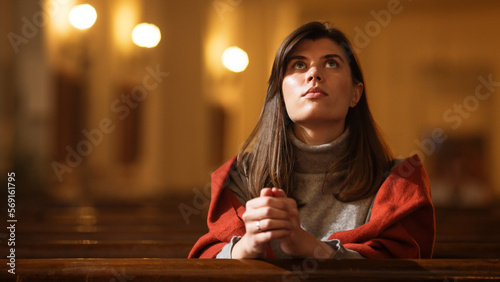 Fotografia A Devout Christian Woman Sits Piously In a Church, Folding Hands For Praying, Seeks Guidance From Her Religious Faith and Spirituality