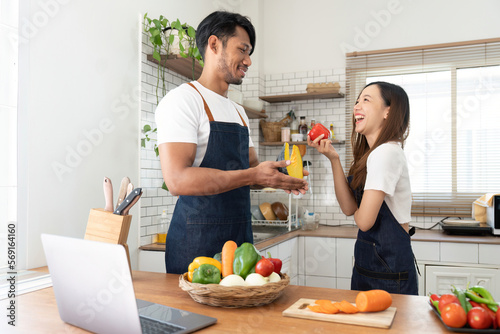 Happy couple preparing food together in kitchen at home ready to cook together