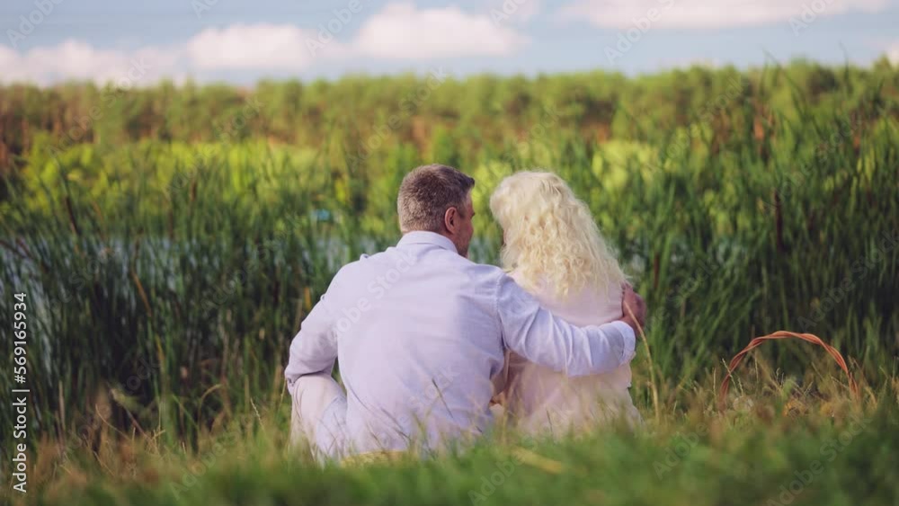 Happy middle-aged couple hugging near lake, enjoying romantic picnic date, love Happy middle-aged couple hugging near lake, enjoying romantic picnic date, love