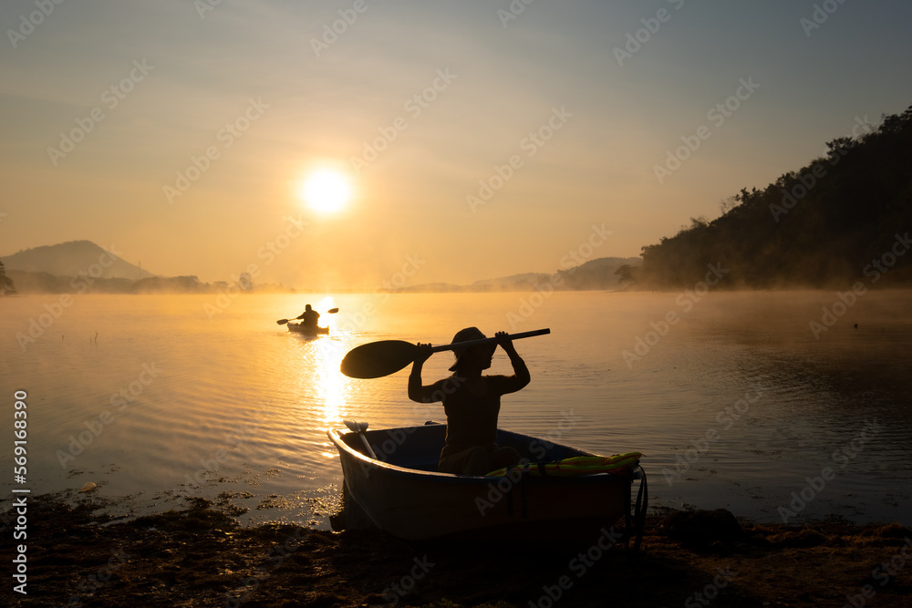Women  mooring a boat to the shore at the reservoir during the sunrise, Harirak forest park Huai Nam Man reservoir Loei Thailand 21 Jan 2023