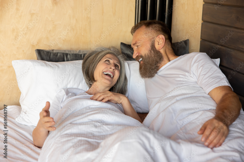 Mature couple staying in bed and looking happy