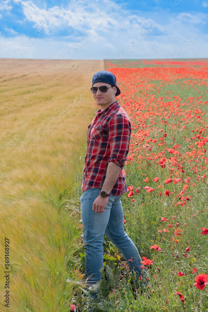 Young Man wearing Red for Valentines day, posing in Flower Field with Poppies. Love and Romance Young Man wearing Red for Valentines day, posing in Flower Field with Poppies. Love and Romance