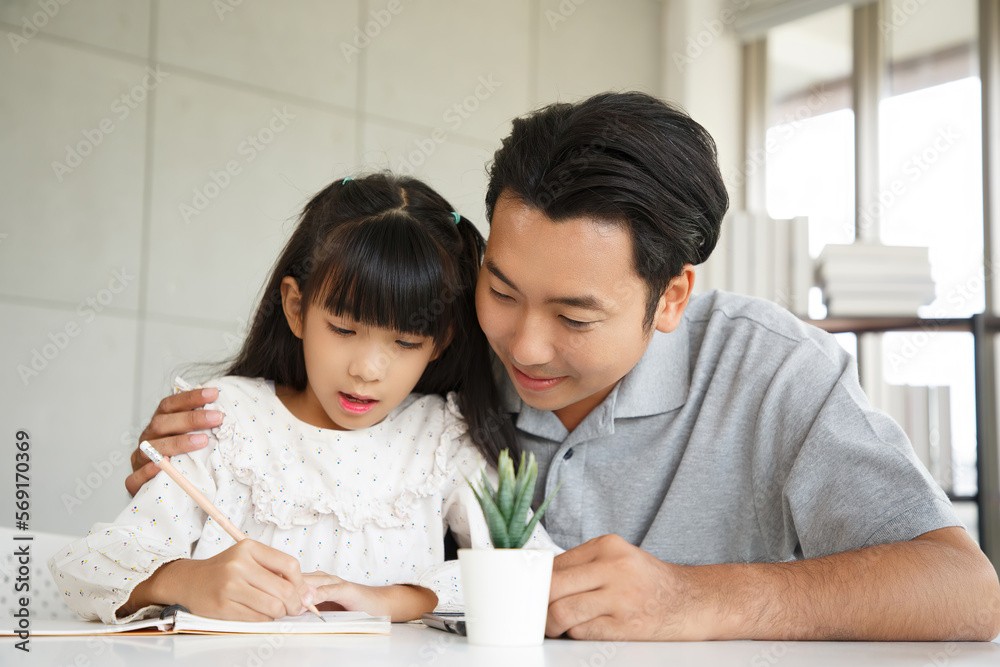 Children education and home school concept : Young asisn father pleased to see little daughters' study success. Excited smiling small child girl enjoying learning and writing with pleasant dad at home Children education and home school concept : Young asisn father pleased to see little daughters' study success. Excited smiling small child girl enjoying learning and writing with pleasant dad at home