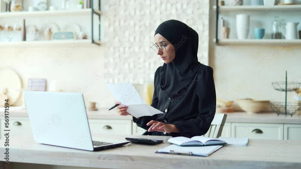 young Muslim woman works from home online, calculates family finances or will study remotely Female in hijab uses laptop computer notes Business woman uses app or website manages personal finances young Muslim woman works from home online, calculates family finances or will study remotely Female in hijab uses laptop computer notes Business woman uses app or website manages personal finances