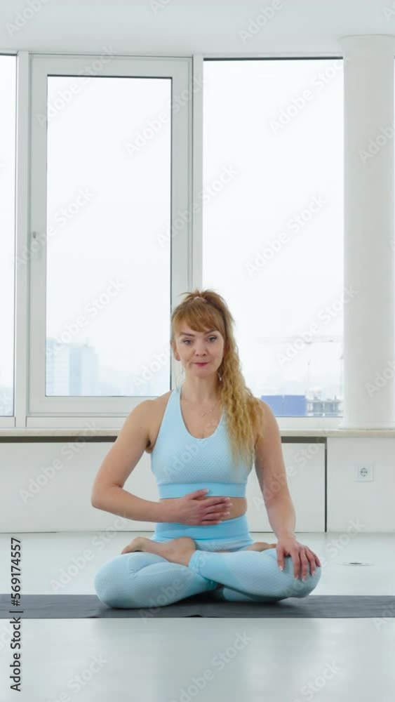 Vertical Screen: Woman in blue sportswear doing breathing exercise in Lotus pose. Yogi female practicing Bhastrika Pranayama in yoga studio. Concept healthy lifestyle Vertical Screen: Woman in blue sportswear doing breathing exercise in Lotus pose. Yogi female practicing Bhastrika Pranayama in yoga studio. Concept healthy lifestyle