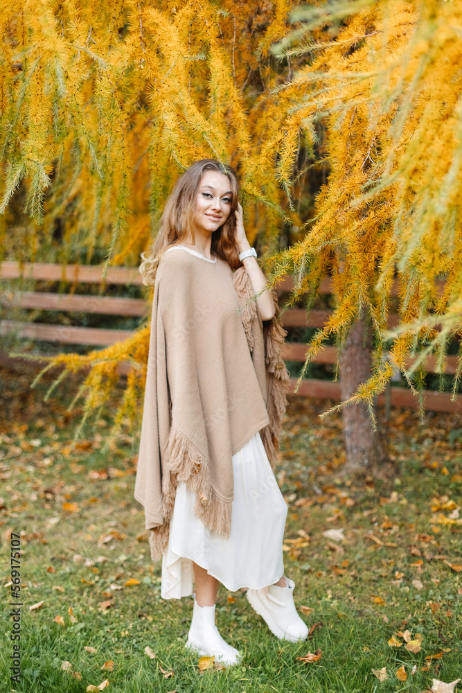Beautiful woman near an autumn tree with yellow dry branches