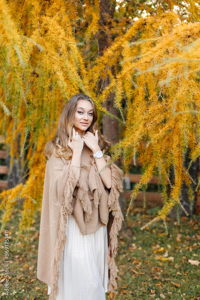 Beautiful woman near an autumn tree with yellow dry branches
