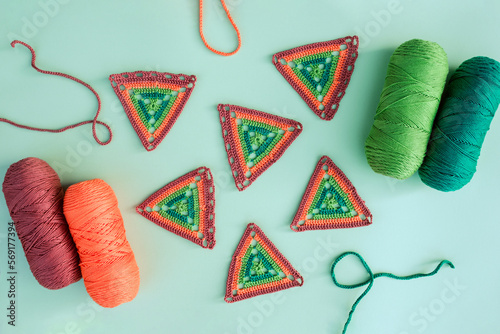 Flat lay of six triangle crochet motifs and four skeins of yarn