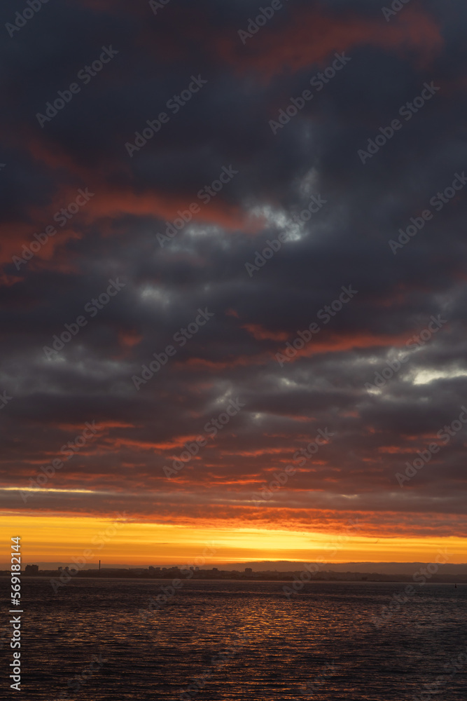 Bright orange sunset and thick clouds above the sea