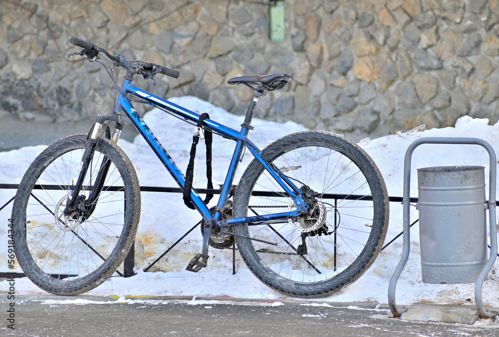 An old bicycle is parked at the fence on a winter day