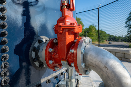 Red water valve on the side of a blue water tank.