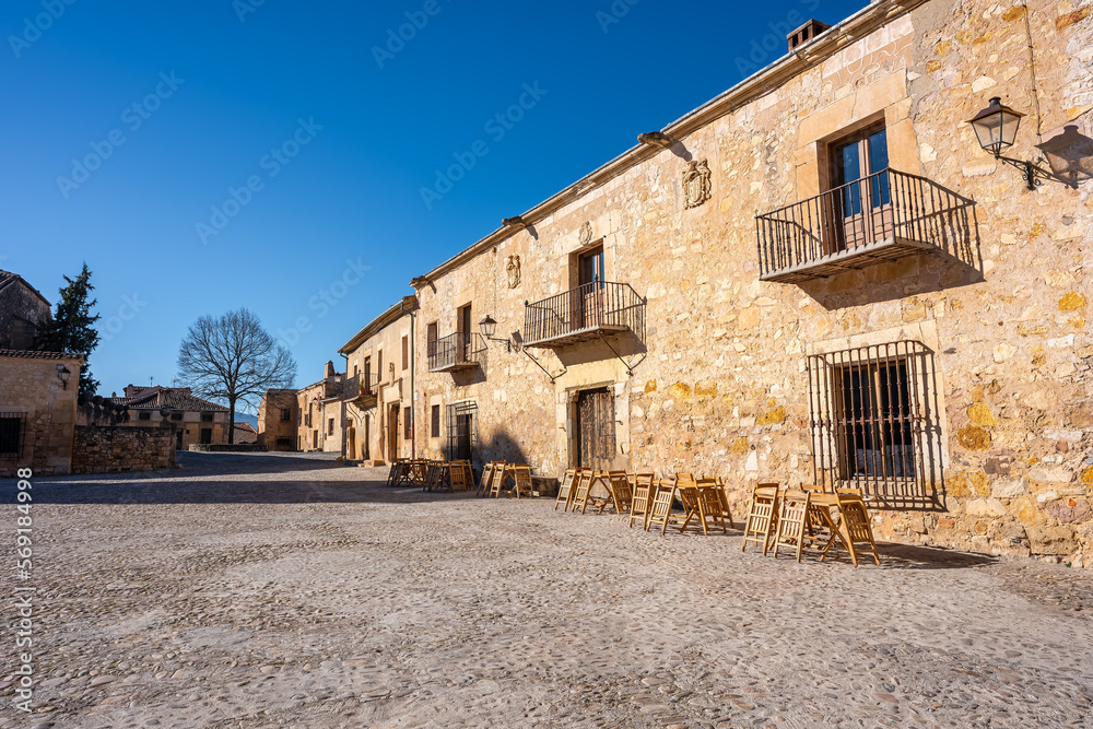 Old stone buildings with grilled balconies and wooden doors in the medieval town of Pedraza, Castile and Leon, Spain.