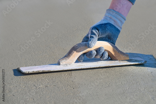 Closeup on a mason using a hand held float on new cement photo