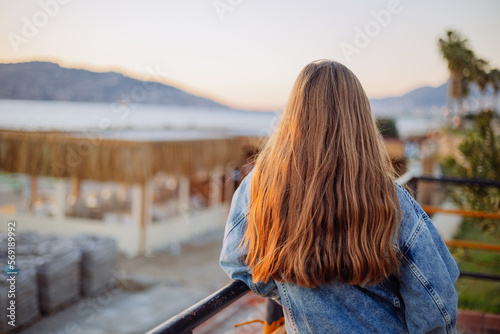 Tableau sur toile Back view of young girl with beautiful long hair on sunset at sea, dark blonde t